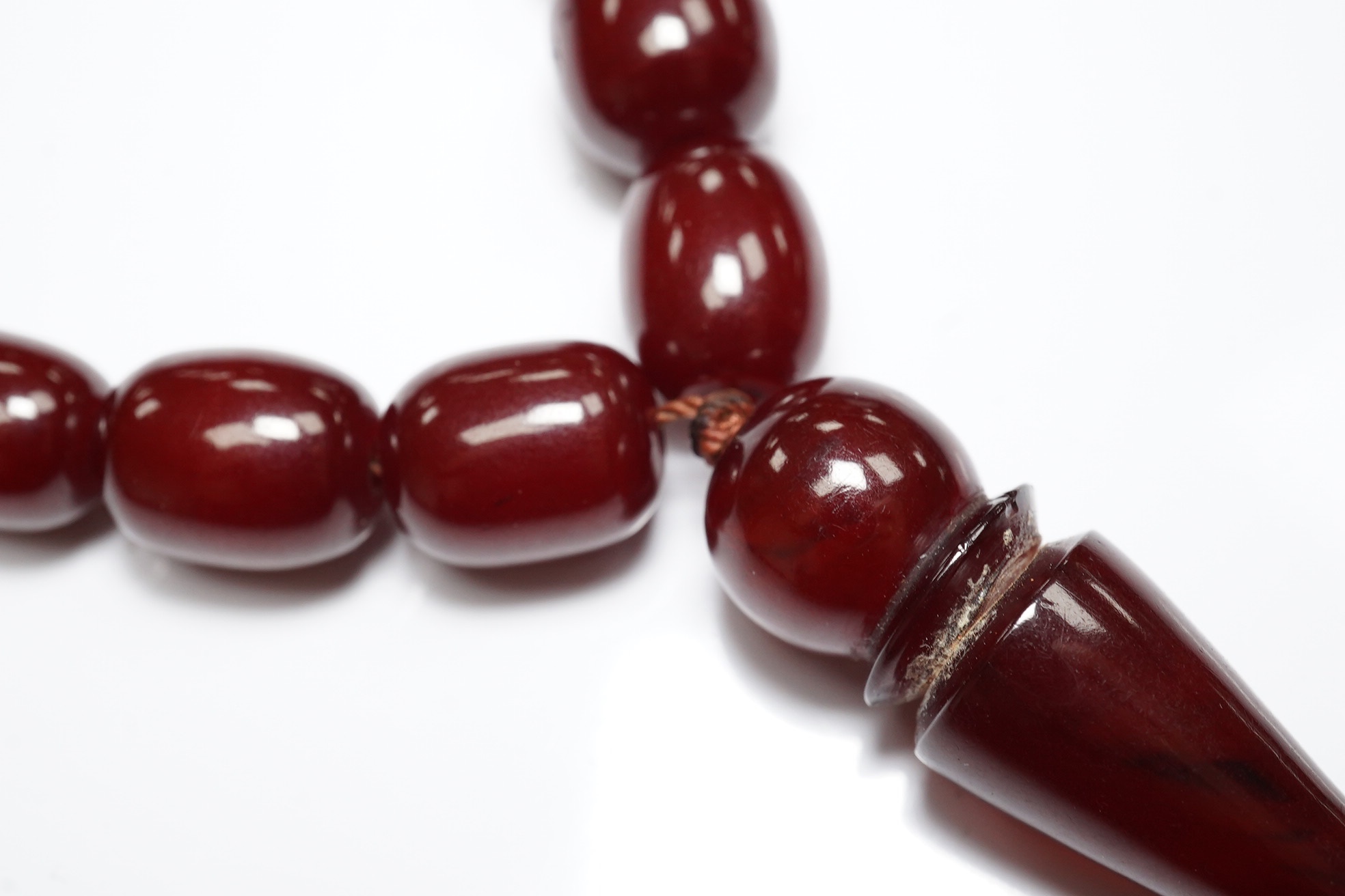 A Persian single strand simulated cherry amber drop bead necklace, 64cm, gross weight 54 grams. Condition - fair to good